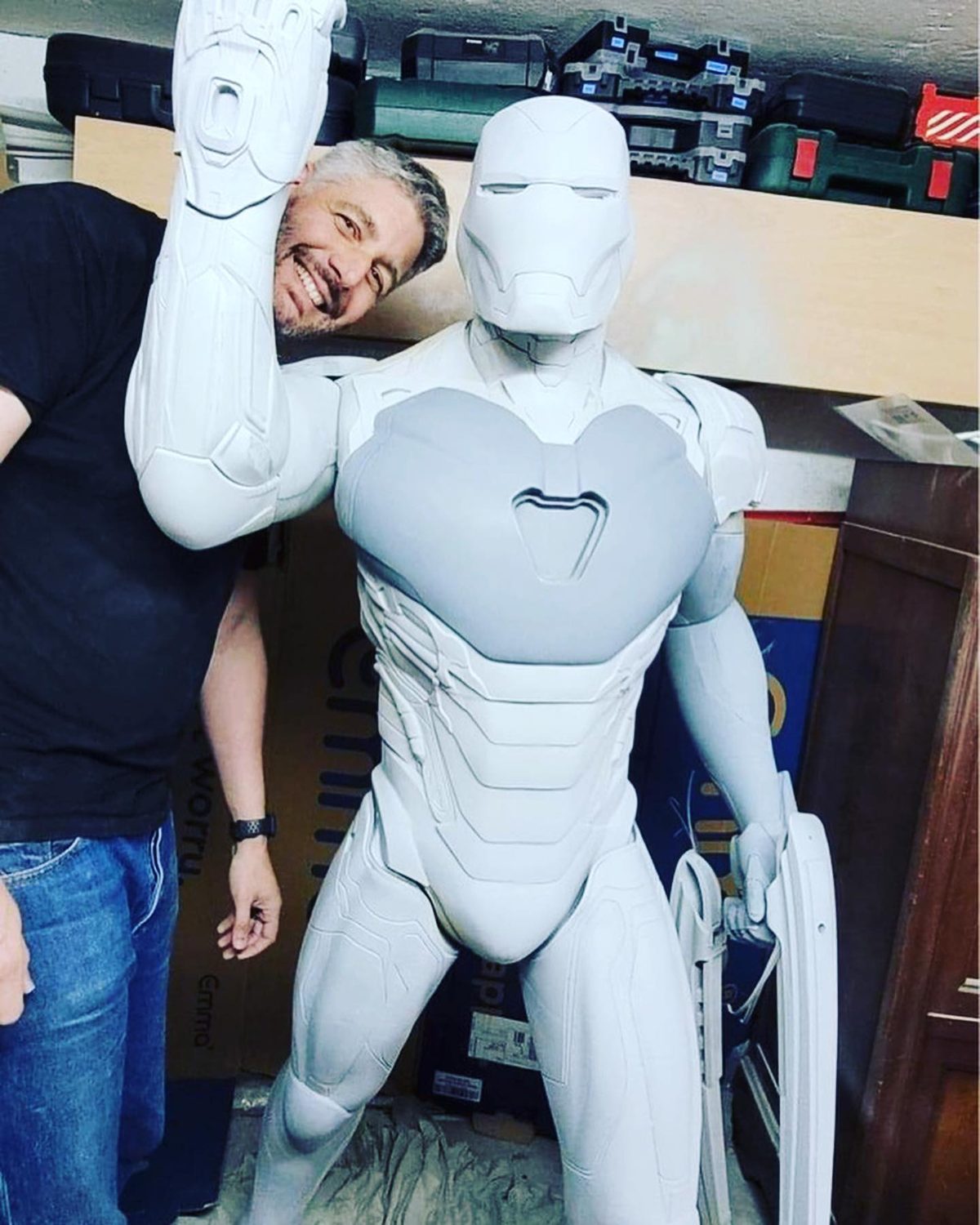 Emmanuel, artisan Manu3D, debout à côté d'une armure grandeur nature qu'il a imprimée en 3D, encore en plastique blanc brut, dans son atelier