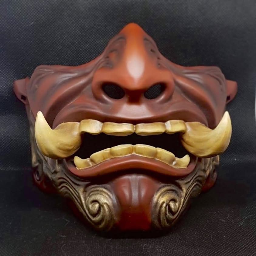 Masque décoratif imprimé en 3D, laqué rouge et or, photographié sur fond sombre