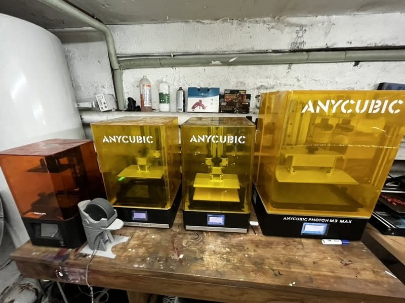 Quatre imprimantes 3D résine Anycubic alignées sur l'établi de l'atelier, avec la station de lavage