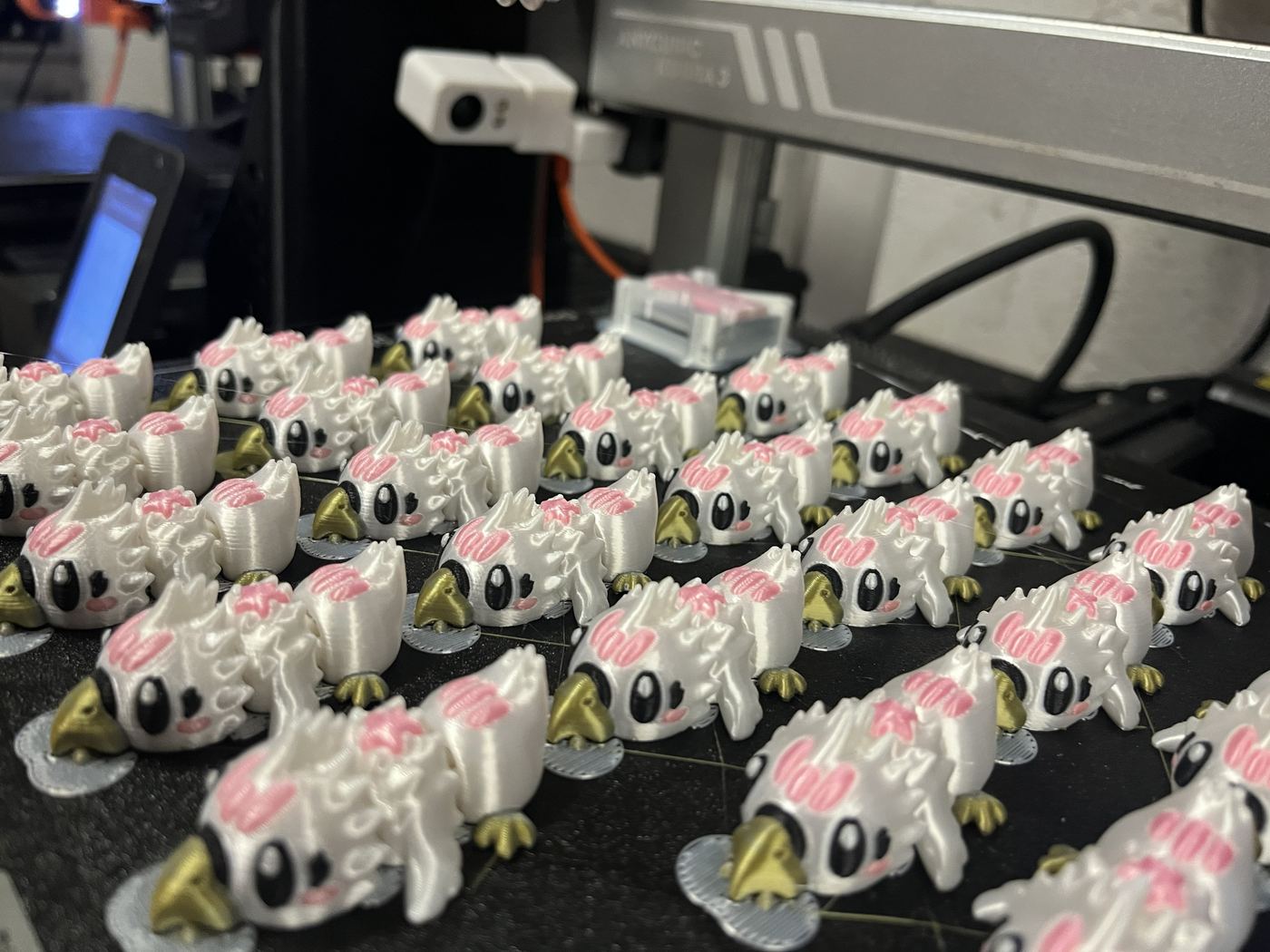 Plateau d'imprimante 3D couvert d'une trentaine de figurines identiques imprimées en plusieurs couleurs