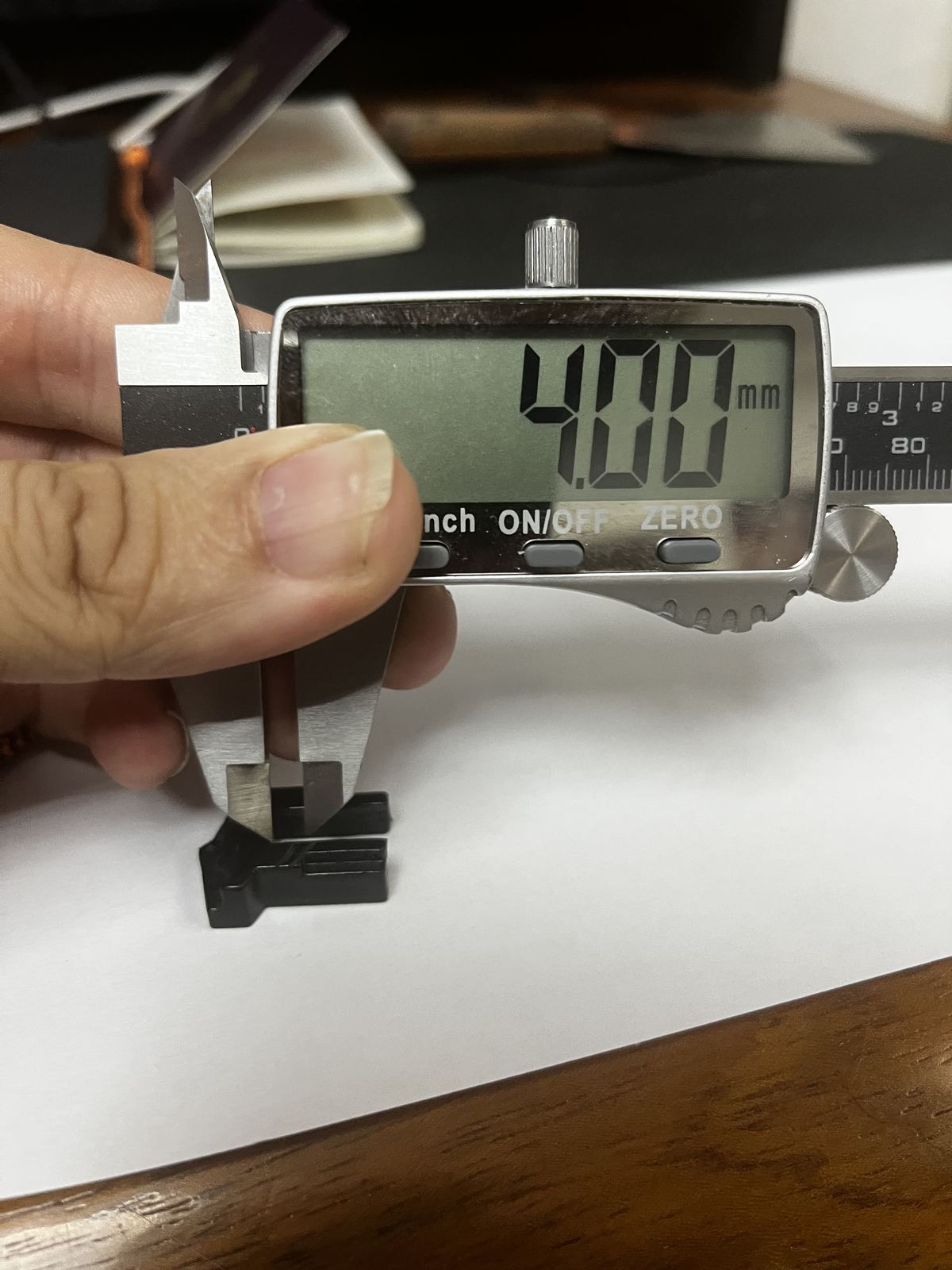 Relevé d'une cote au pied à coulisse numérique sur une petite pièce noire imprimée en 3D, affichage à 4,00 mm