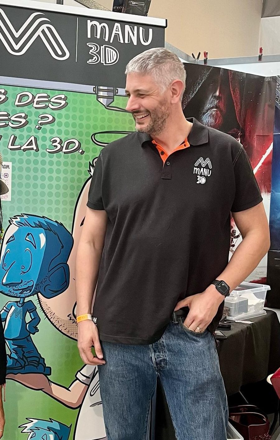 Emmanuel en polo Manu3D devant le kakémono de l'atelier, sur son stand lors d'un salon